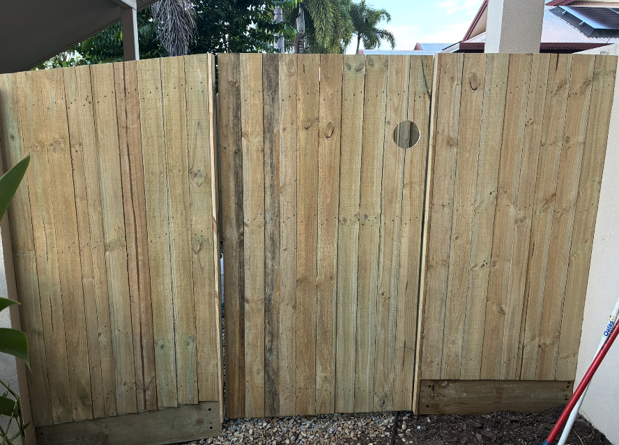 Handcrafted treated pine timber side gates with porthole detail at a Cairns home
